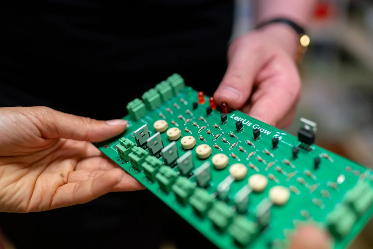 Engineers holding a green electronic control board during a technical review