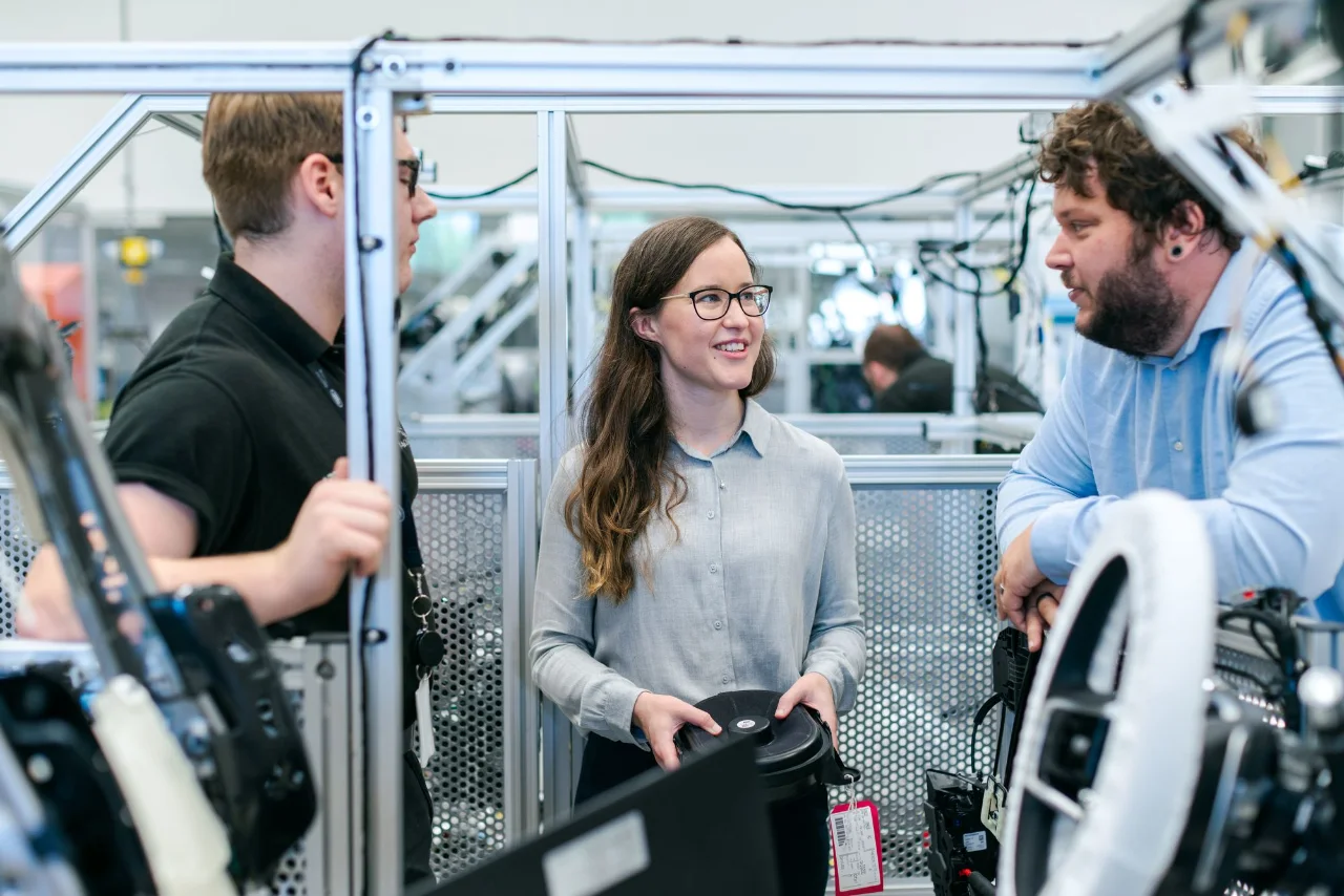 Three engineers discussing hardware in an engineering workshop