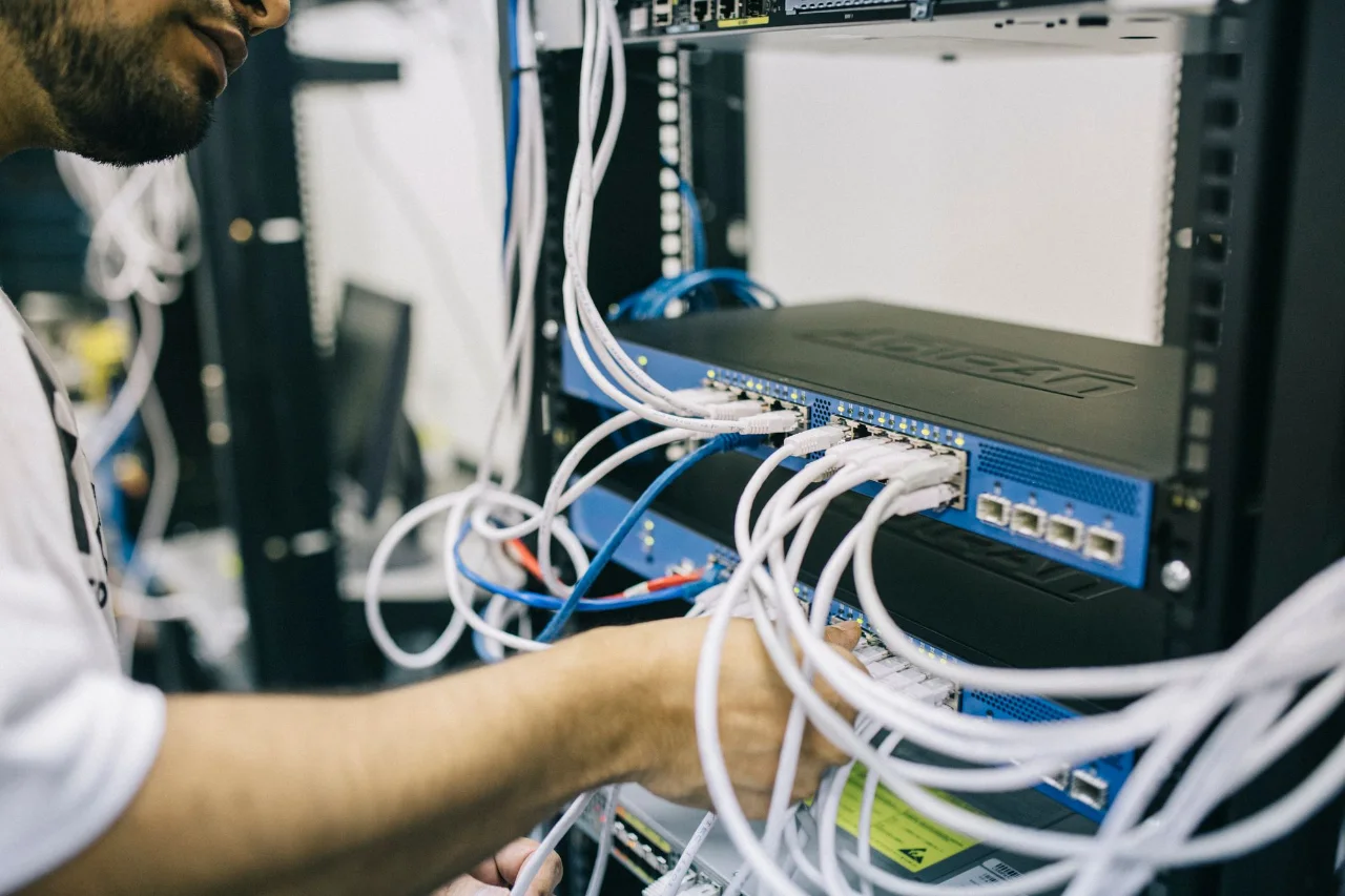 Network engineer connecting cables to switches in an equipment rack
