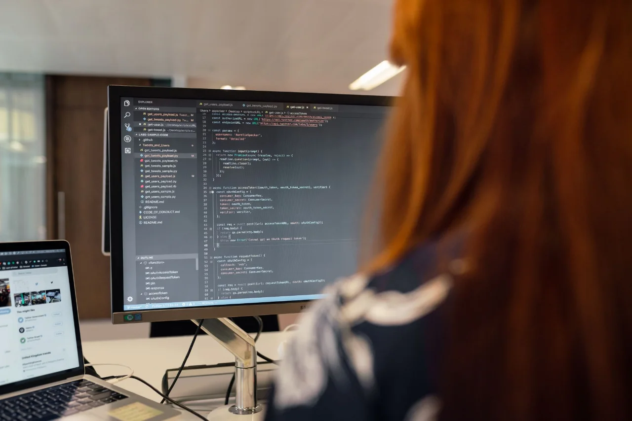 Software engineer working at a desktop computer with code on screen